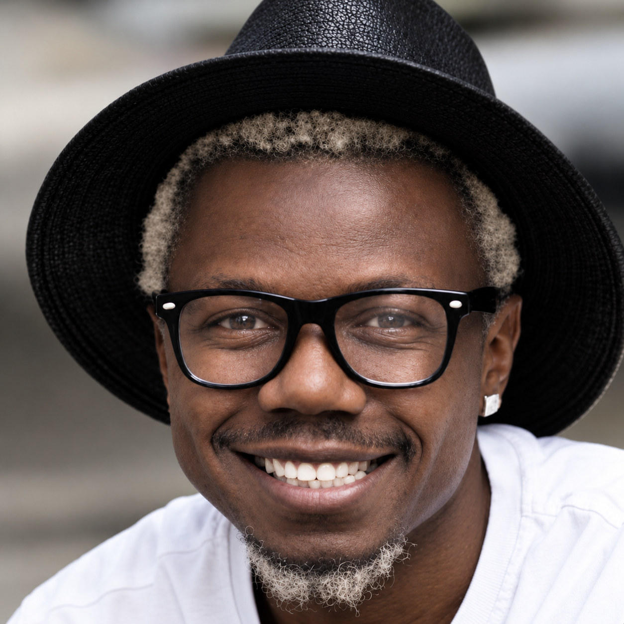 Prince Desire smiling in a black hat and glasses.