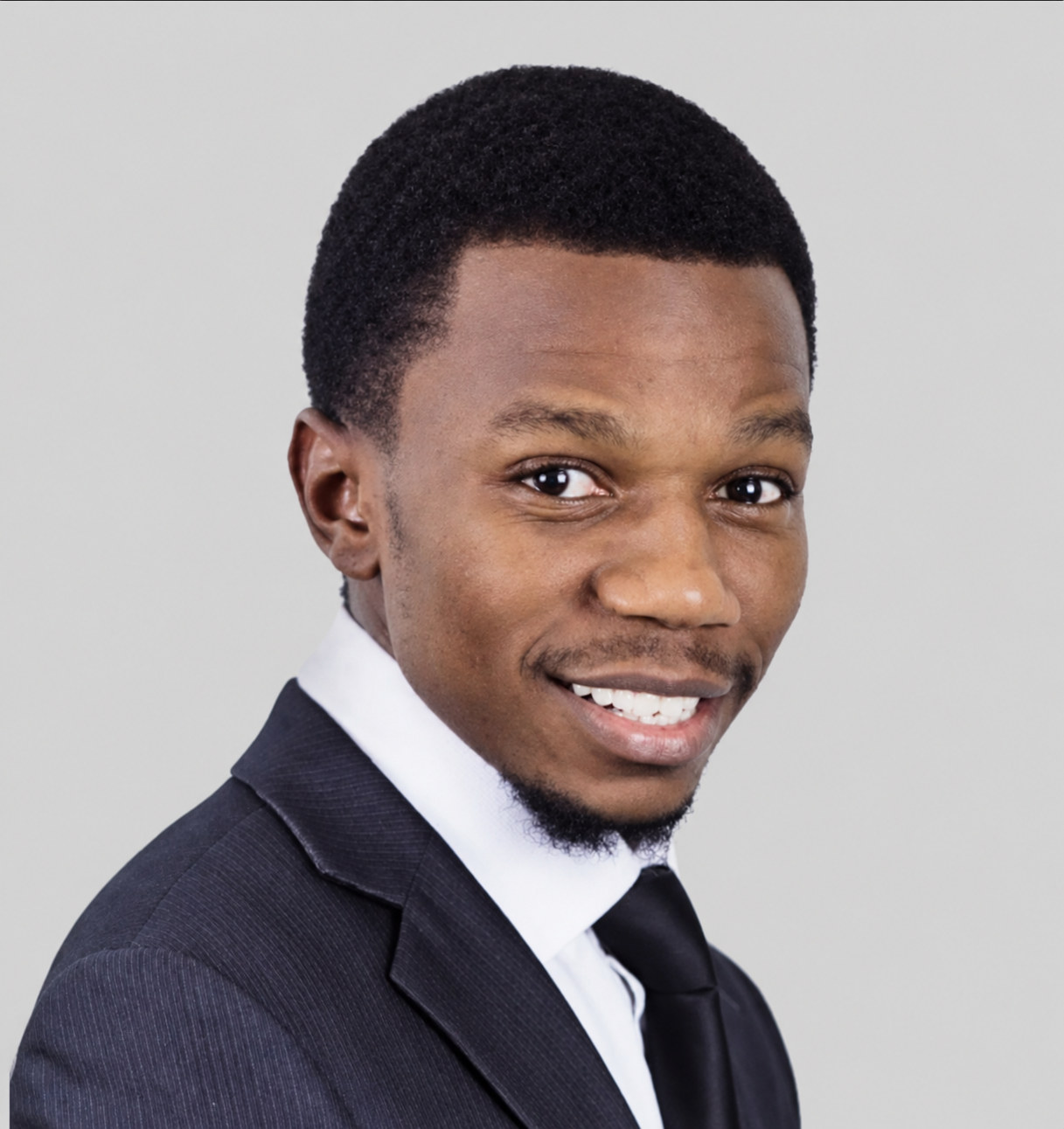 Prince Desire Magomo in a dark suit and tie, smiling.