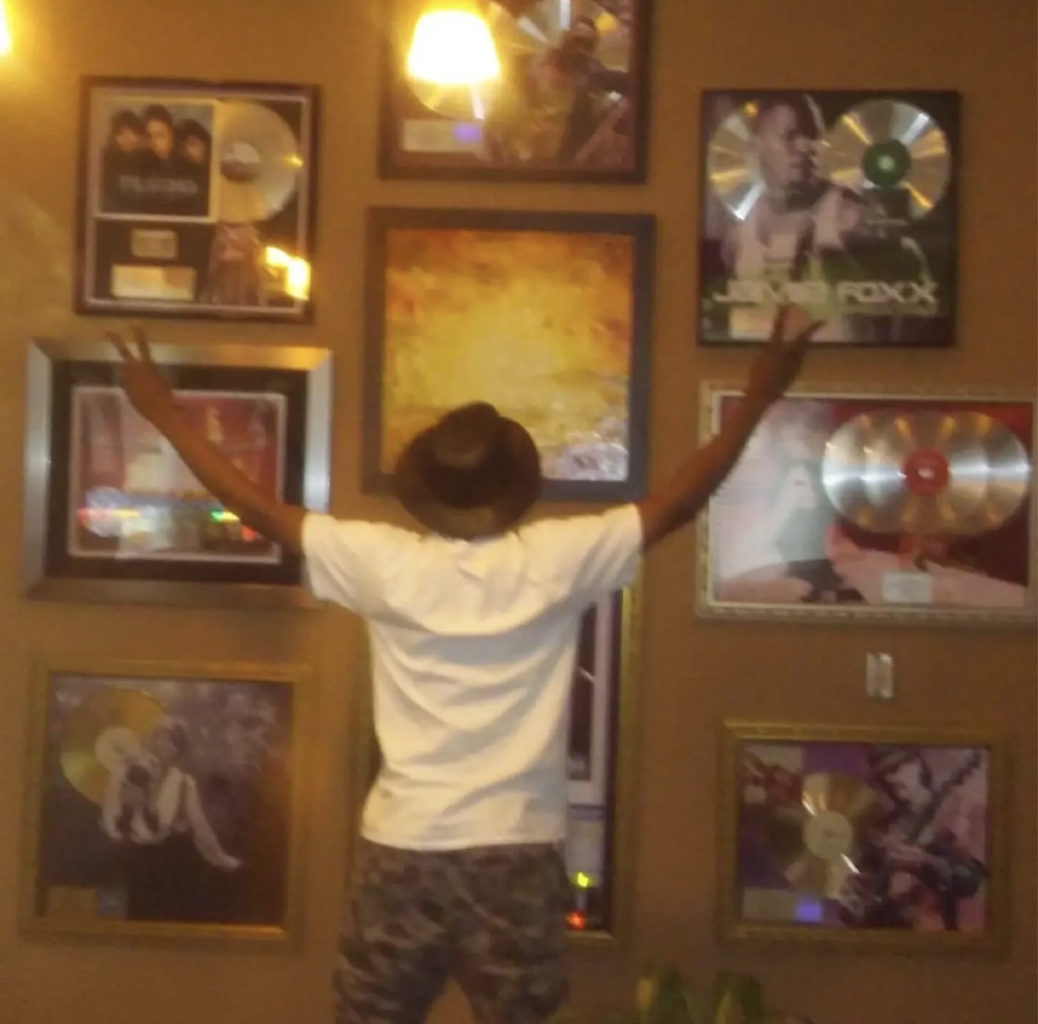 Prince Desire standing in front of music plaques and records.